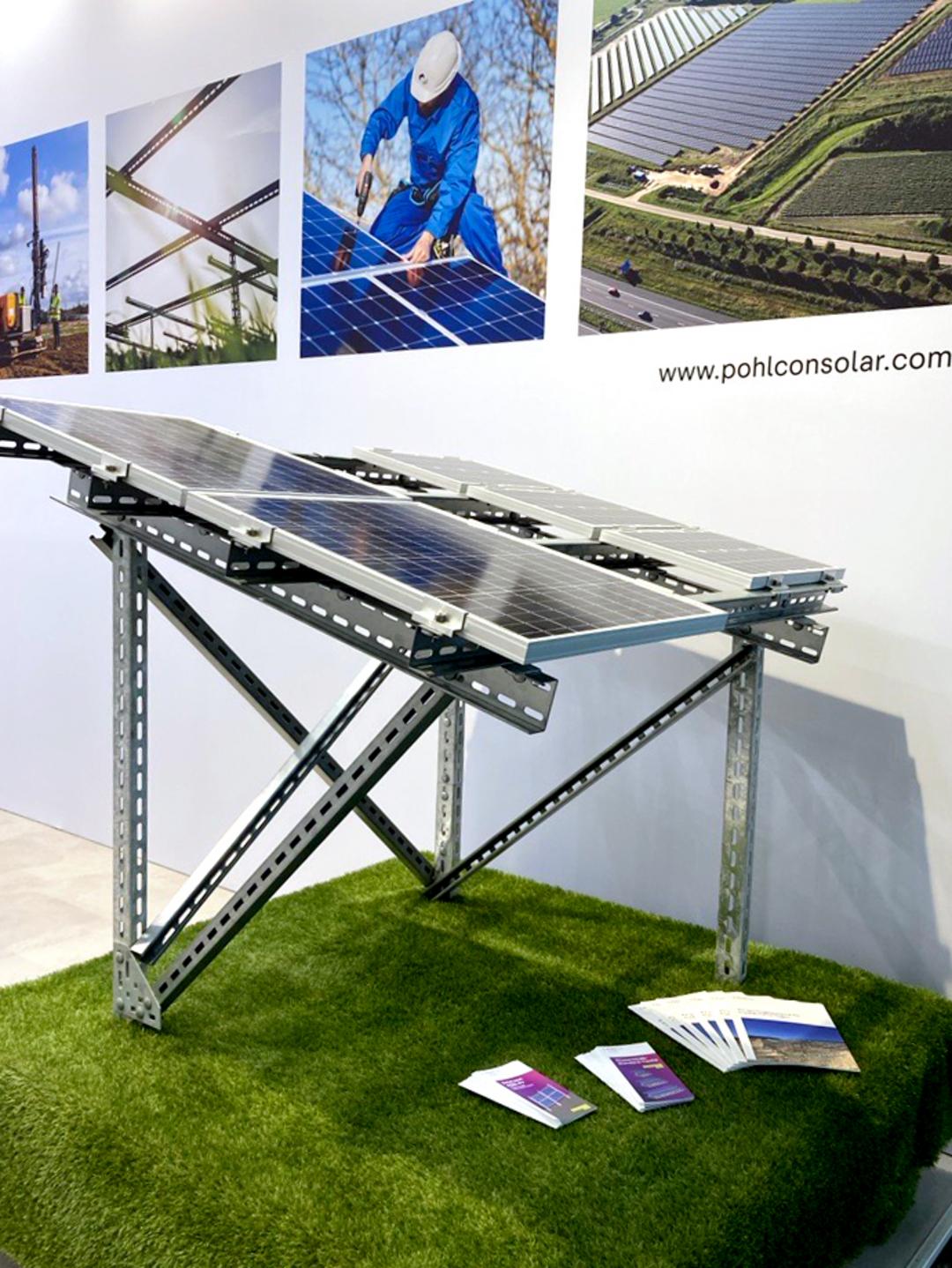 Ein Muster eines Solar-Montagesystems mit darauf montierten Solarpanelen mit einer mit Fotos bedruckten Wand im Hintergrund.