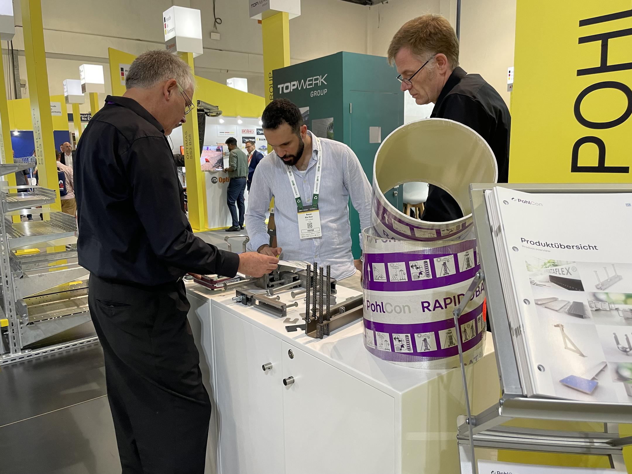 Messestand mit Ausstellungsstücken Schalrohre und Ankerschienen, Messepersonal und Besuchern