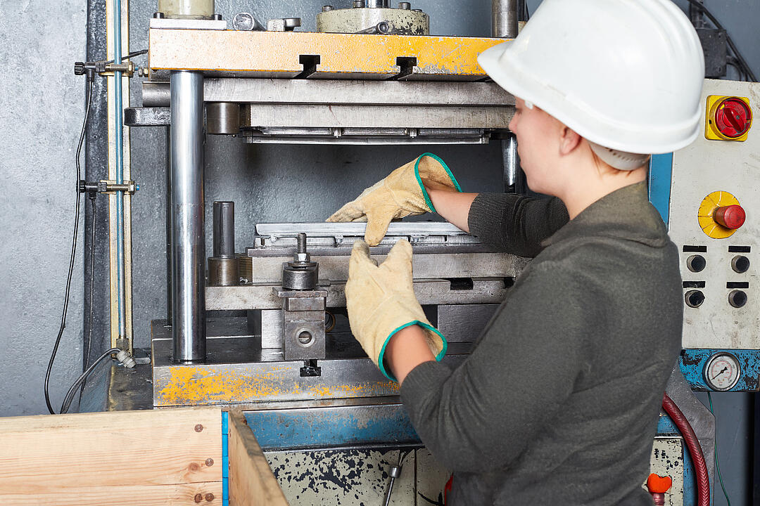 Produktionsmitarbeiterin bearbeitet ein Werkstück an einer Biegemaschine