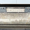 Metallhalterung mit Schrauben an Betonwand, darüber braunes Bauelement mit Klebestreifen.