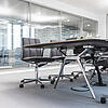 Ein helles Büro mit einer Glaswand im Hintergrund und Tisch und Stühlen im Vordergrund.