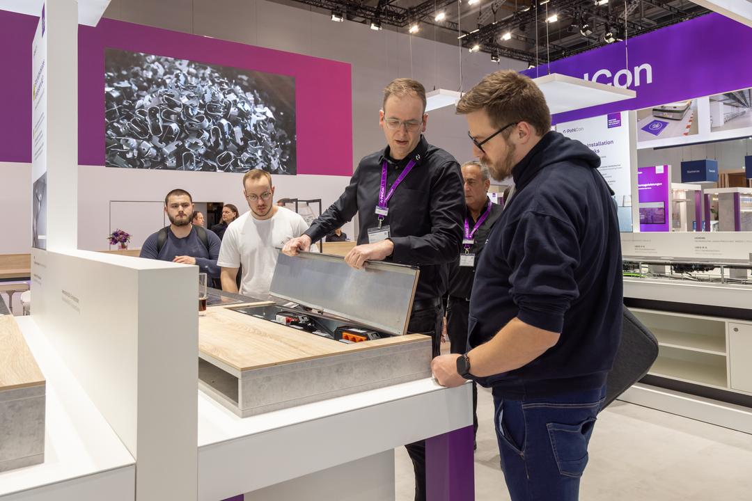 Messestand mit Besuchern an einem Exponat