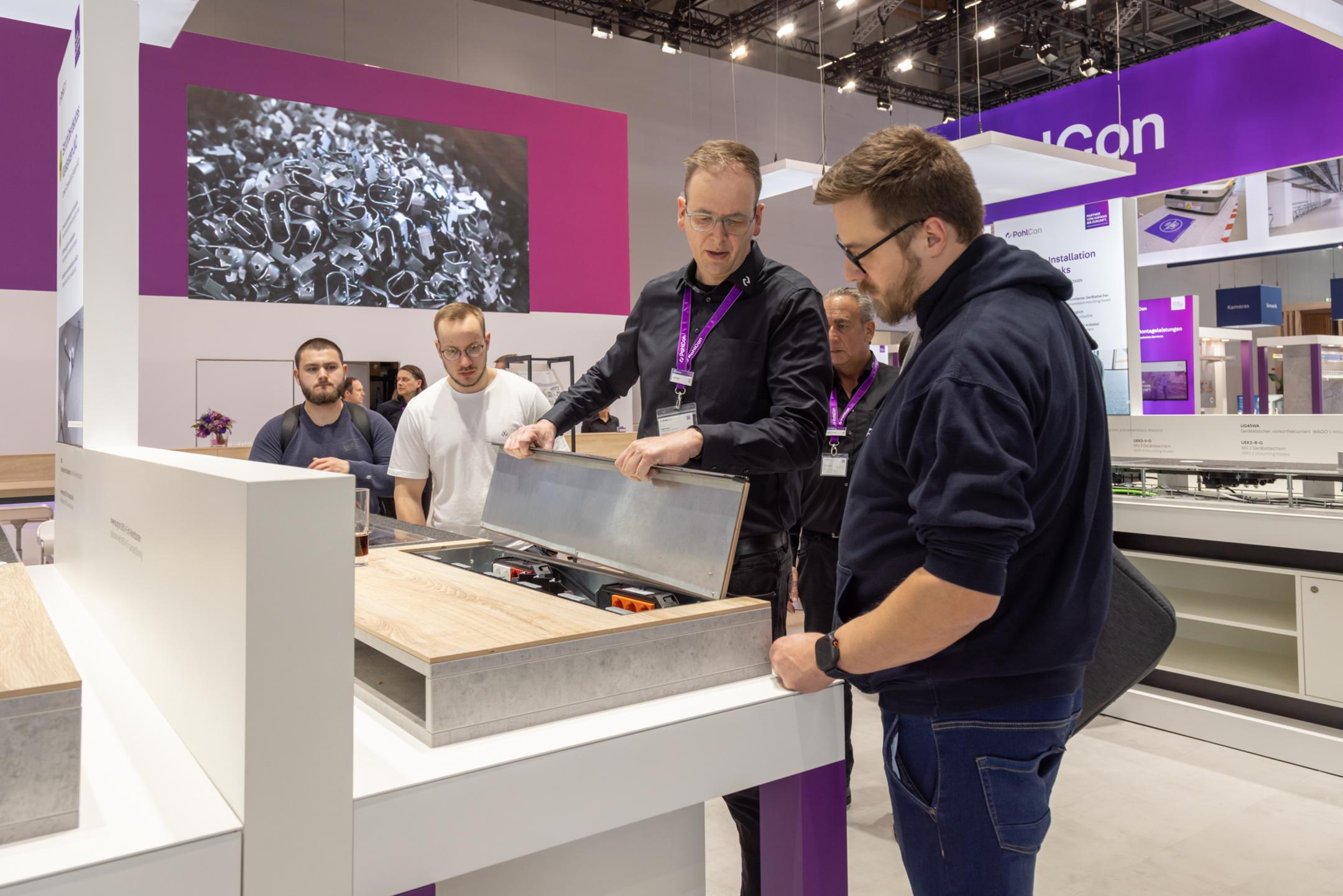 Messestand mit Besuchern an einem Exponat