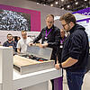 Messestand mit Besuchern an einem Exponat