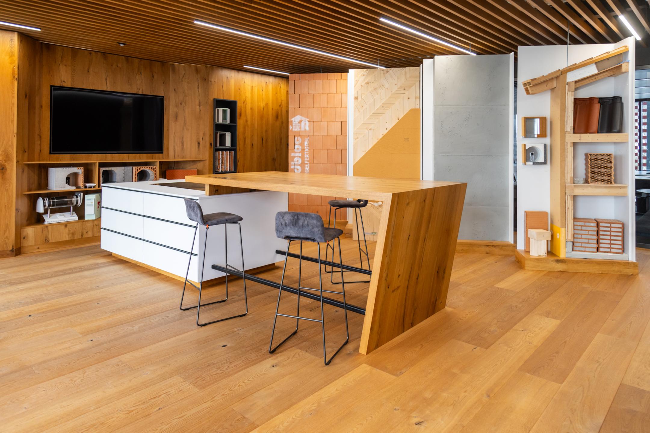 Holzverkleideter Raum mit einem Tisch und Stühlen, im Hintergrund sind verschiedene Bauelemente zu erkennen.
