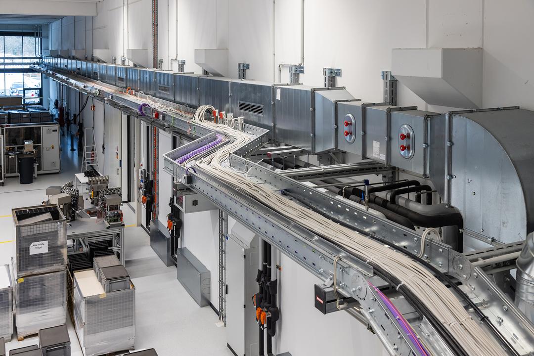 Moderne Produktionshalle mit Detailsicht auf Kabeltragsystem und Schacht an der Wand