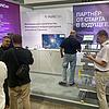Messestand mit Infotafeln und Besuchern und Modell mit Kabeltragsystemen