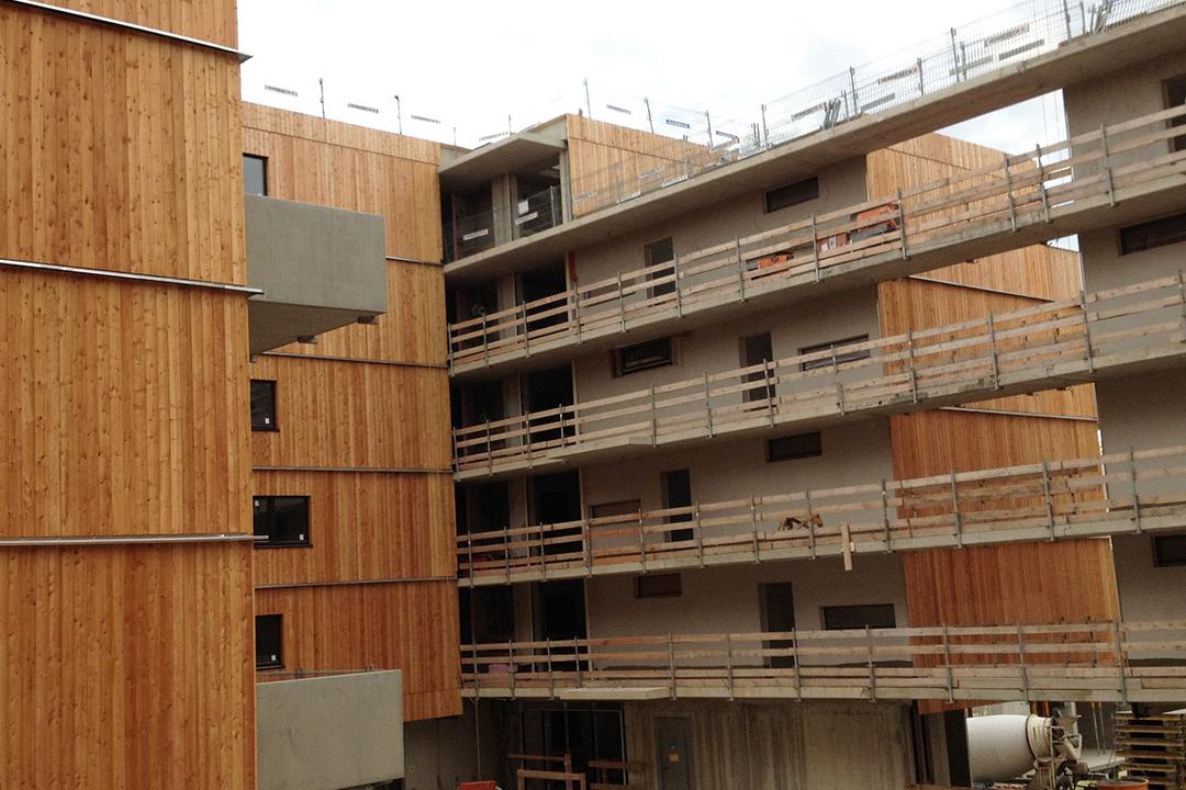 Mehrstöckiger Rohbau mit Holzverkleidung, Betonstruktur und provisorischen Geländern