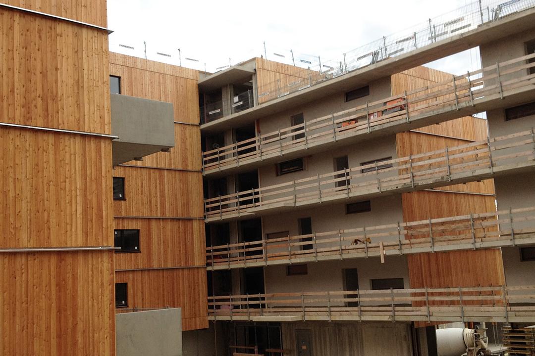 Mehrstöckiger Rohbau mit Holzverkleidung, Betonstruktur und provisorischen Geländern