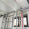Installierte Kabeltrassen mit geführten Leitungen an Wand und Decke in einem Technikraum mit Fenster und sichtbaren Rohrleitungen