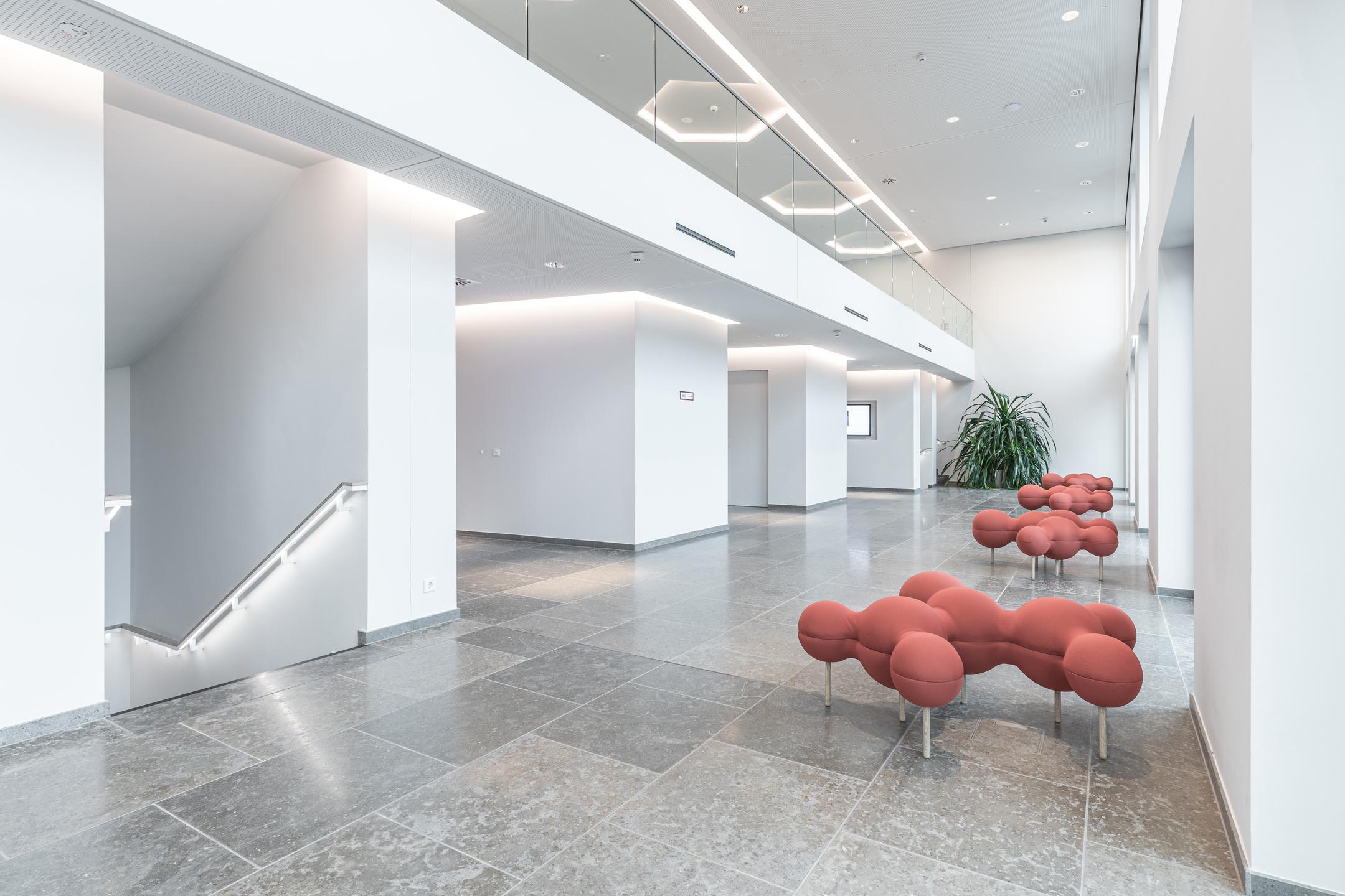 Blick in eine moderne Büroumgebung mit Treppenhaus und futuristisch anmutenden Sitzmöbeln.