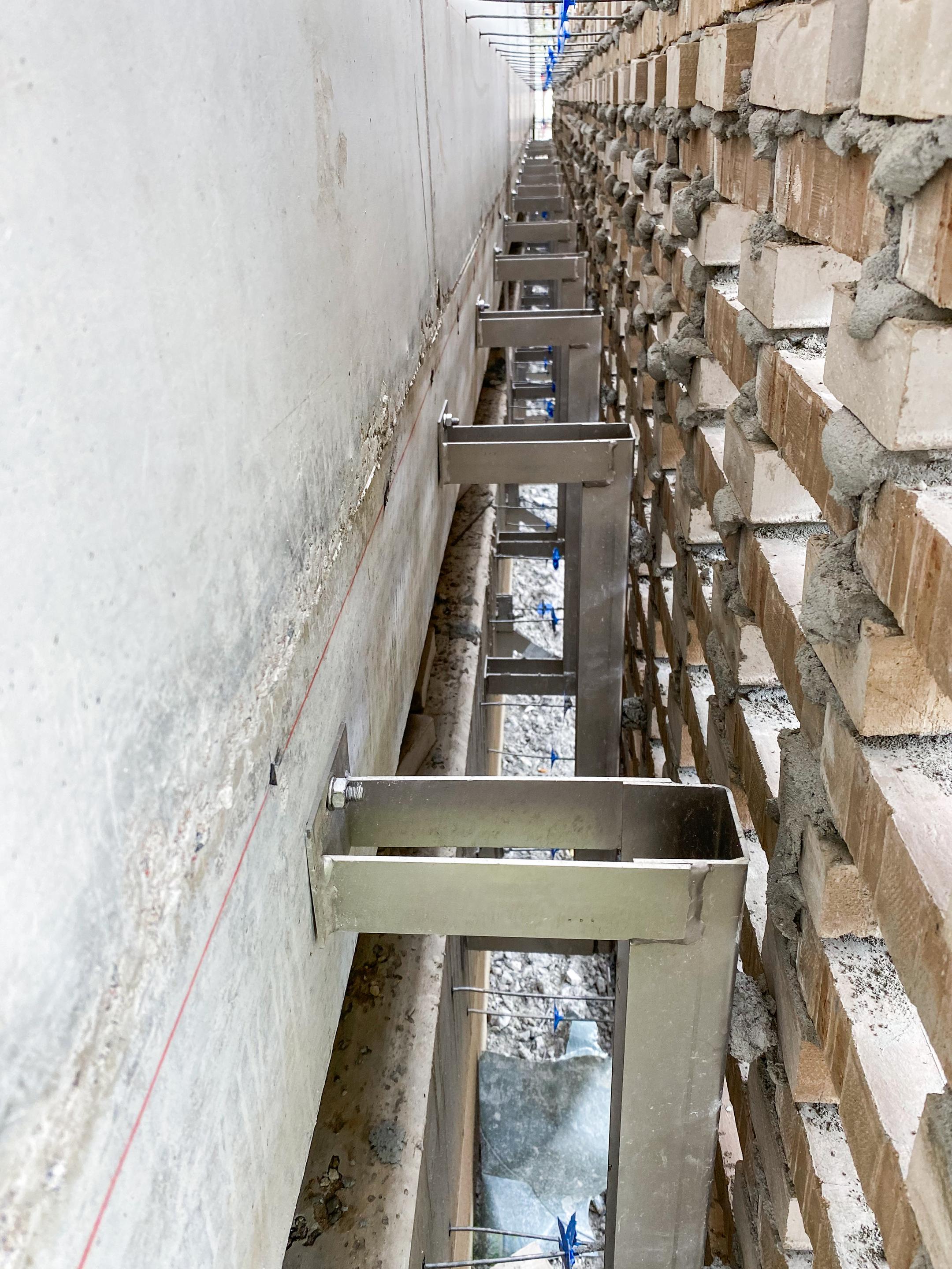 Blick zwischen Betonwand und Vorhangfassade mit Windposts