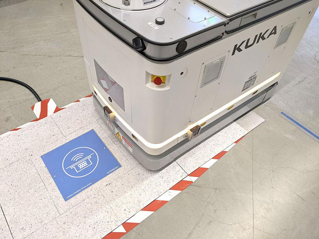 Automatisierter Transportroboter fährt über eine blaue induktive Ladeeinheit
