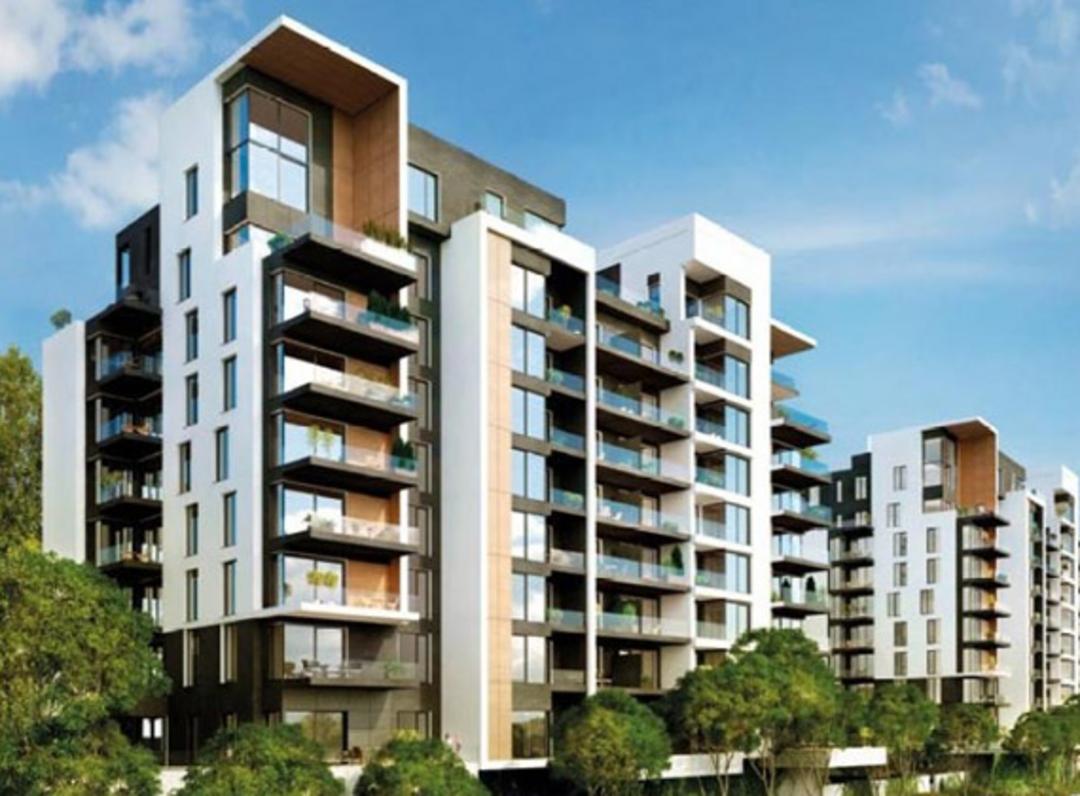 Mehrstöckiges modernes Gebäude mit Balkonen und Bäume im Vordergrund