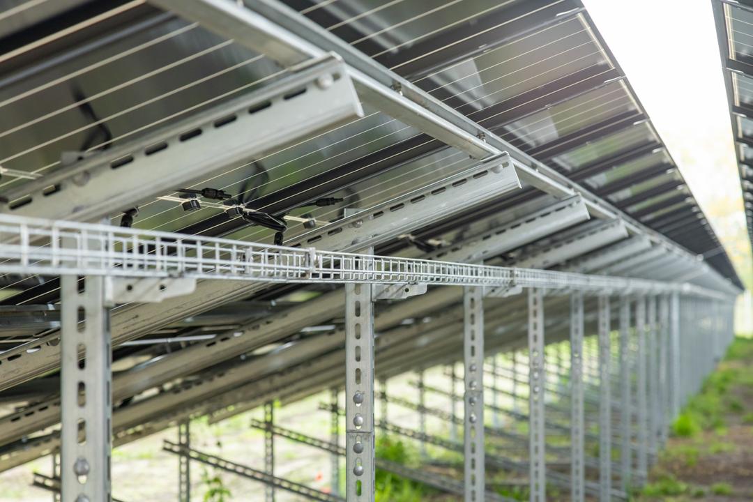 Nahaufnahme einer Unterkonstruktion einer Photovoltaikanlage mit Blick auf die Solarmodule und Gitterbahnen.