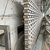Baustelle mit halbfertiger Mauer aus weißen Ziegeln und Gerüst im Außenbereich