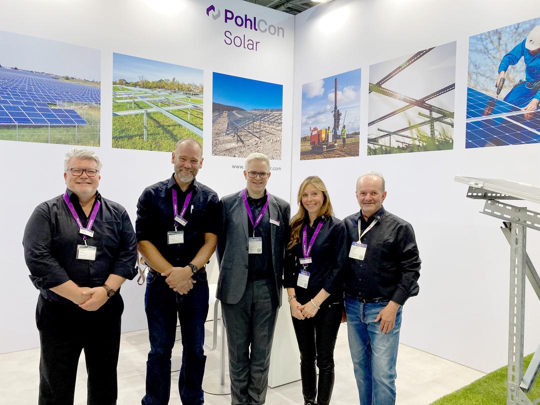 Fünf Mitarbeiter von PohlCon Solar stehen nebeneinander vor ihrem Messestand