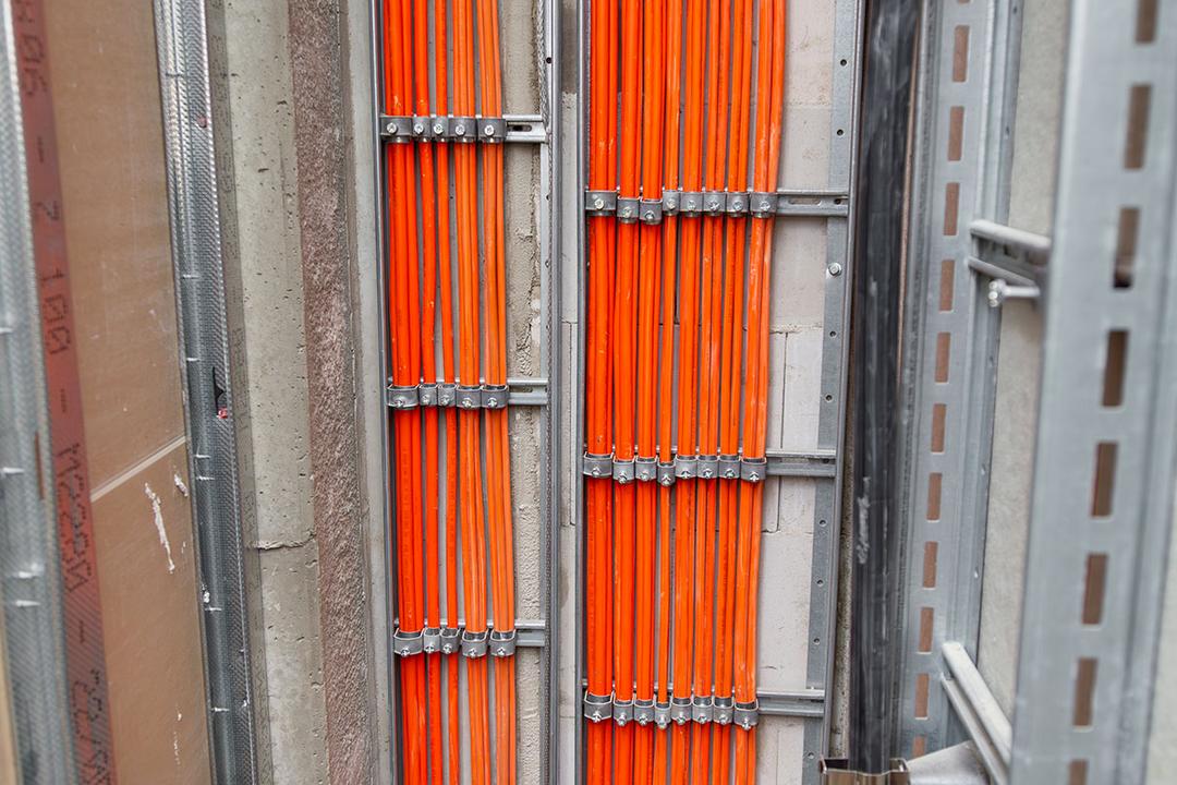 Orange Kabel werden durch metallene Leitungen geführt.