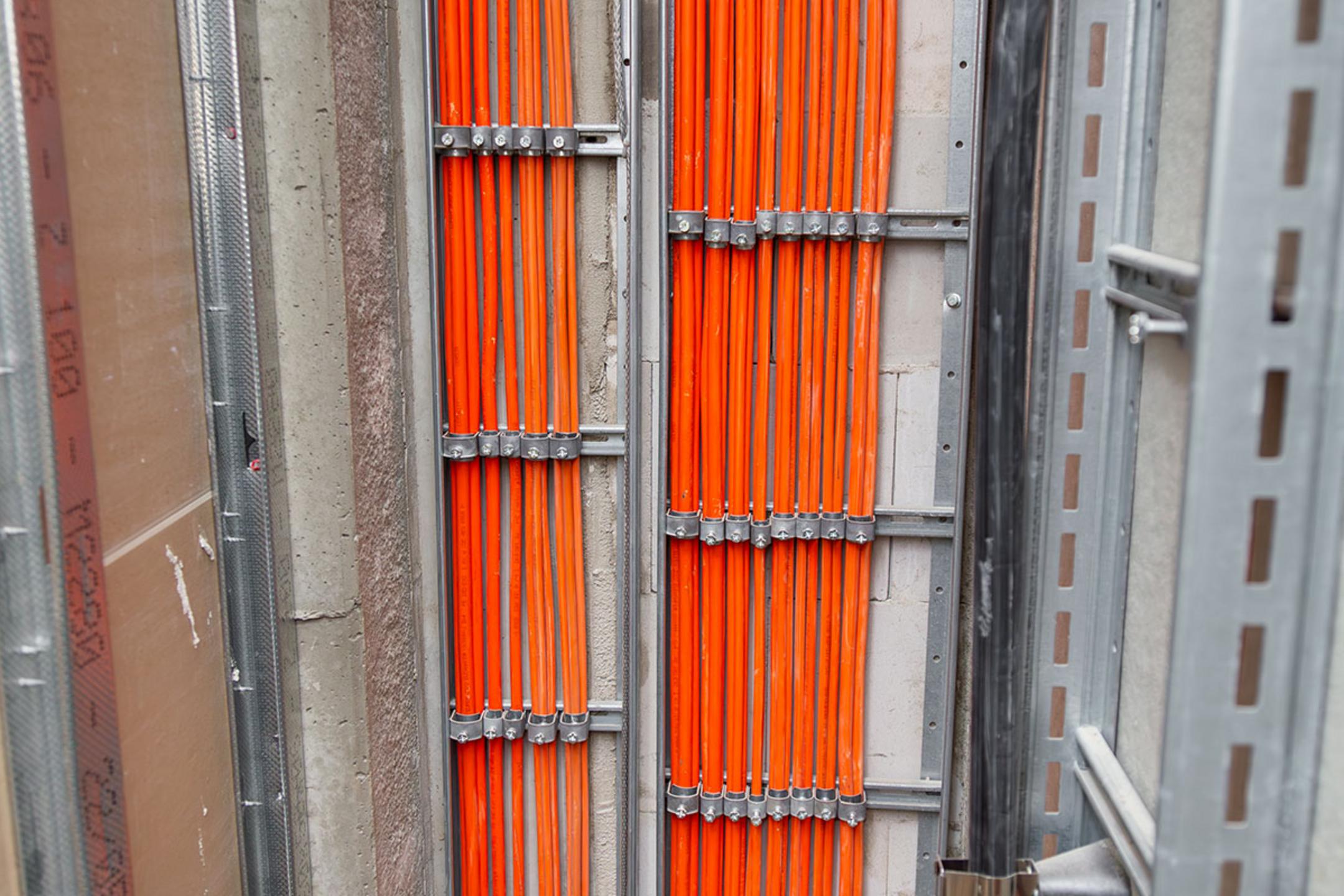 Orange Kabel werden durch metallene Leitungen geführt.