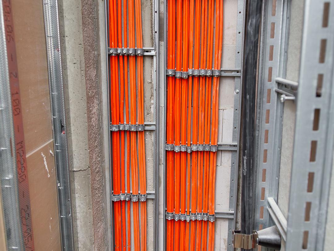 Orange Kabel werden durch metallene Leitungen geführt.