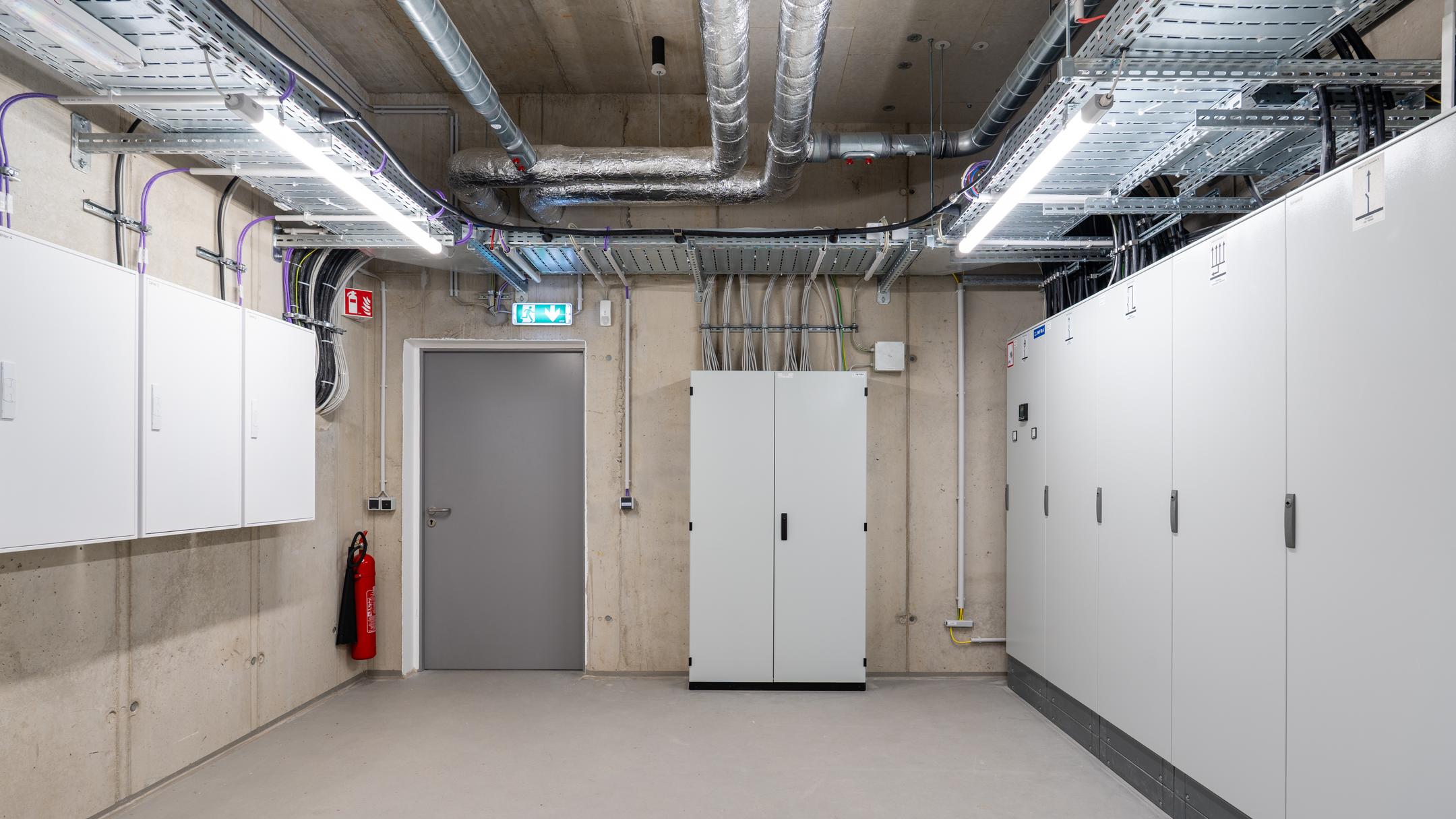 Raum mit mehreren Schränken, Kabel an den Wänden, Kabelrinnen an der Decke.
