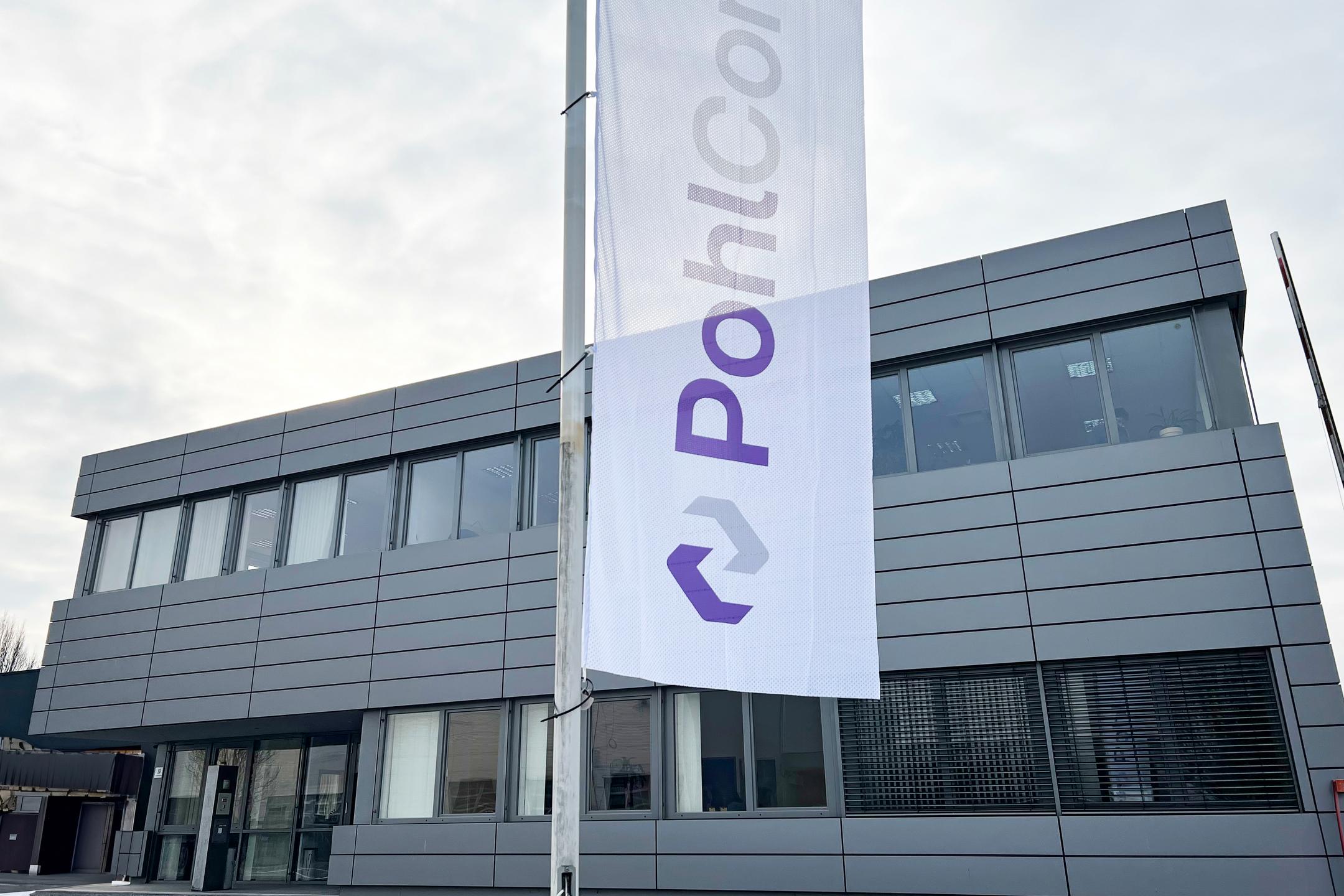 Bürogebäude mit Fahne im Vordergrund. Darauf steht "PohlCon"