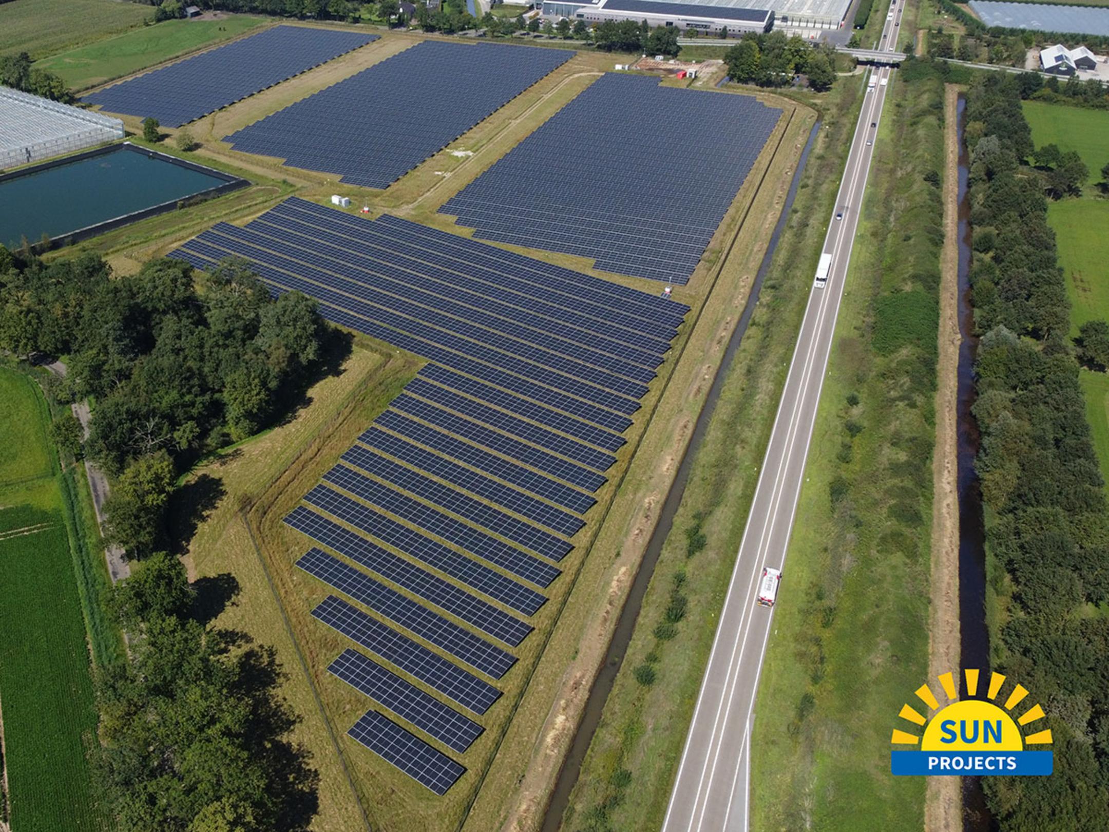 Luftaufnahme einer landwirtschafltichen Fläche mit Solarpanelen, eine Autobahn grenzt an