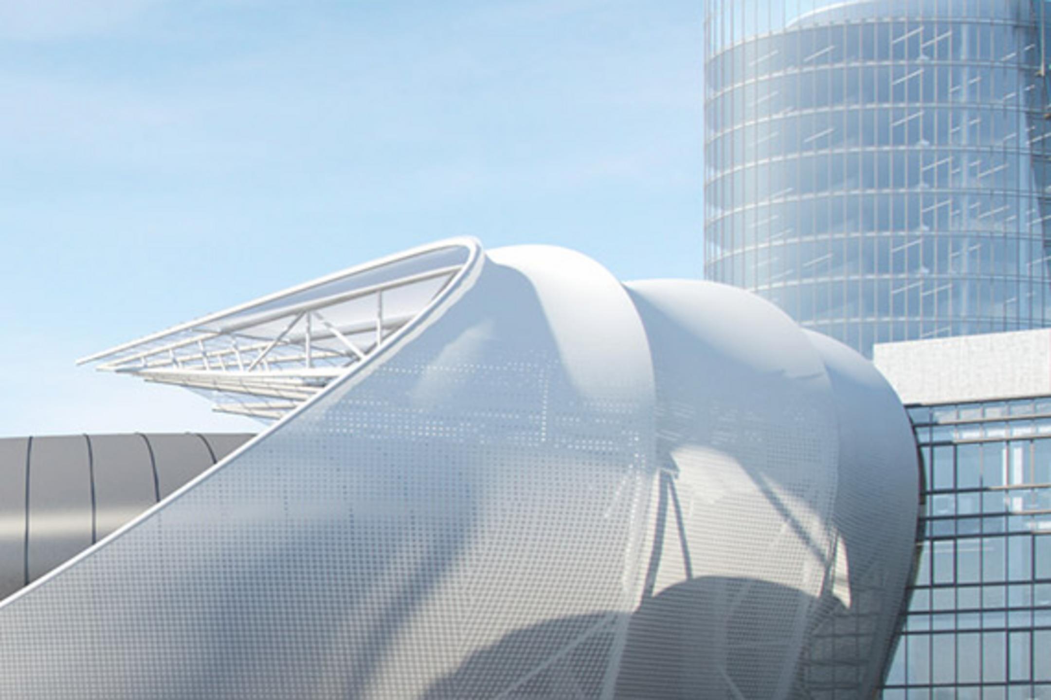 Moderner Gebäudekomplex mit geschwungenen Fassadenelementen und gläsernem Turm vor blauem Himmel