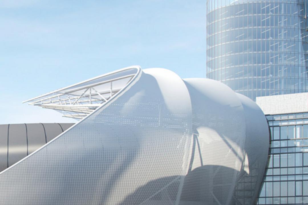 Moderner Gebäudekomplex mit geschwungenen Fassadenelementen und gläsernem Turm vor blauem Himmel