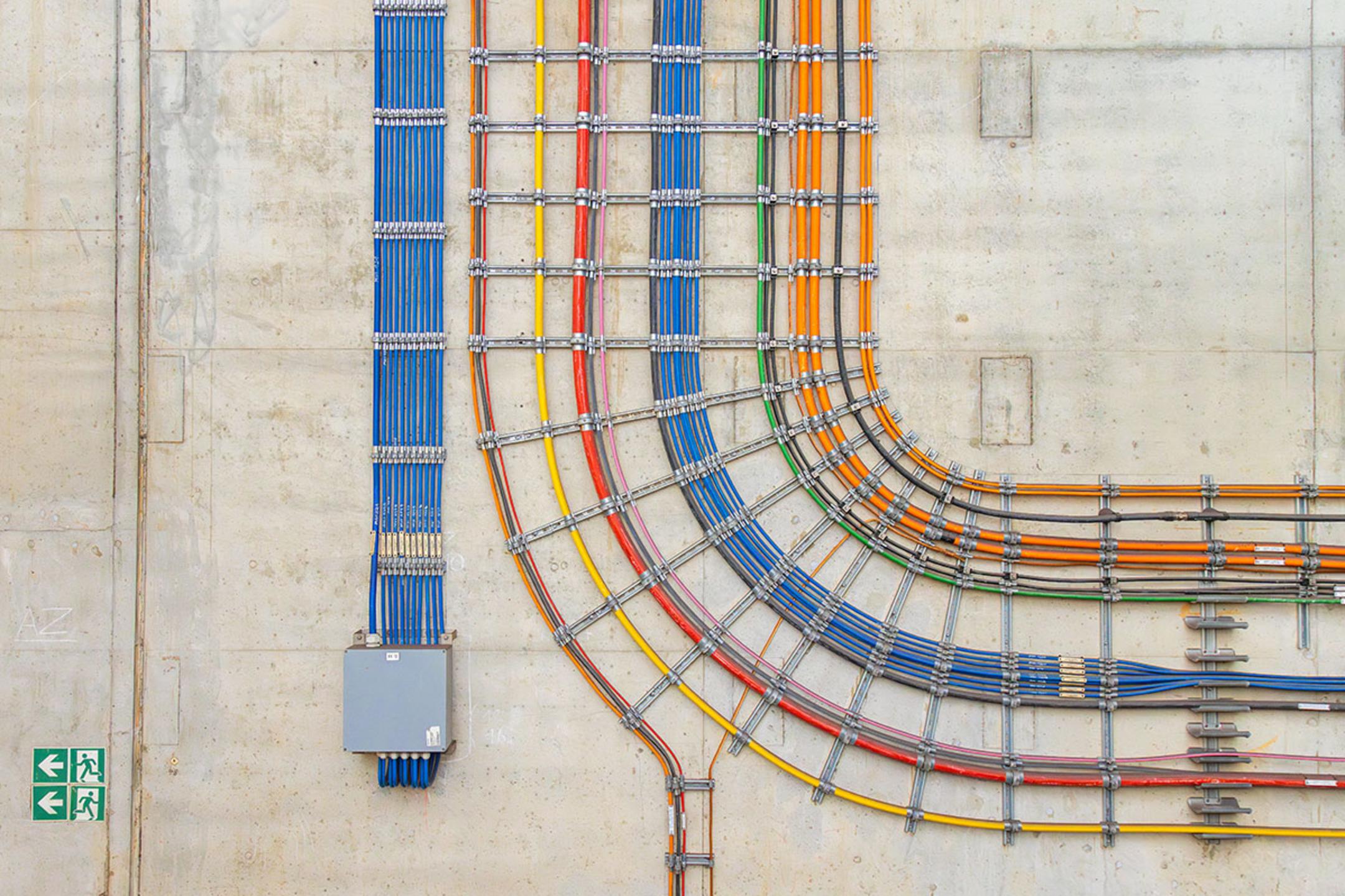 Farbcodierte Kabel in präziser Verlegung an einer Betonwand