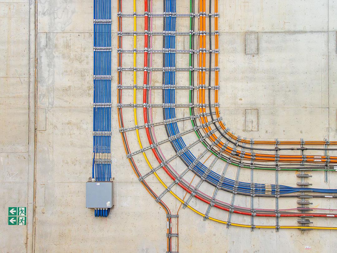 Farbcodierte Kabel in präziser Verlegung an einer Betonwand