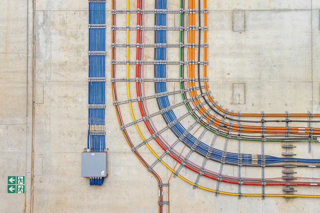 Farbcodierte Kabel in präziser Verlegung an einer Betonwand