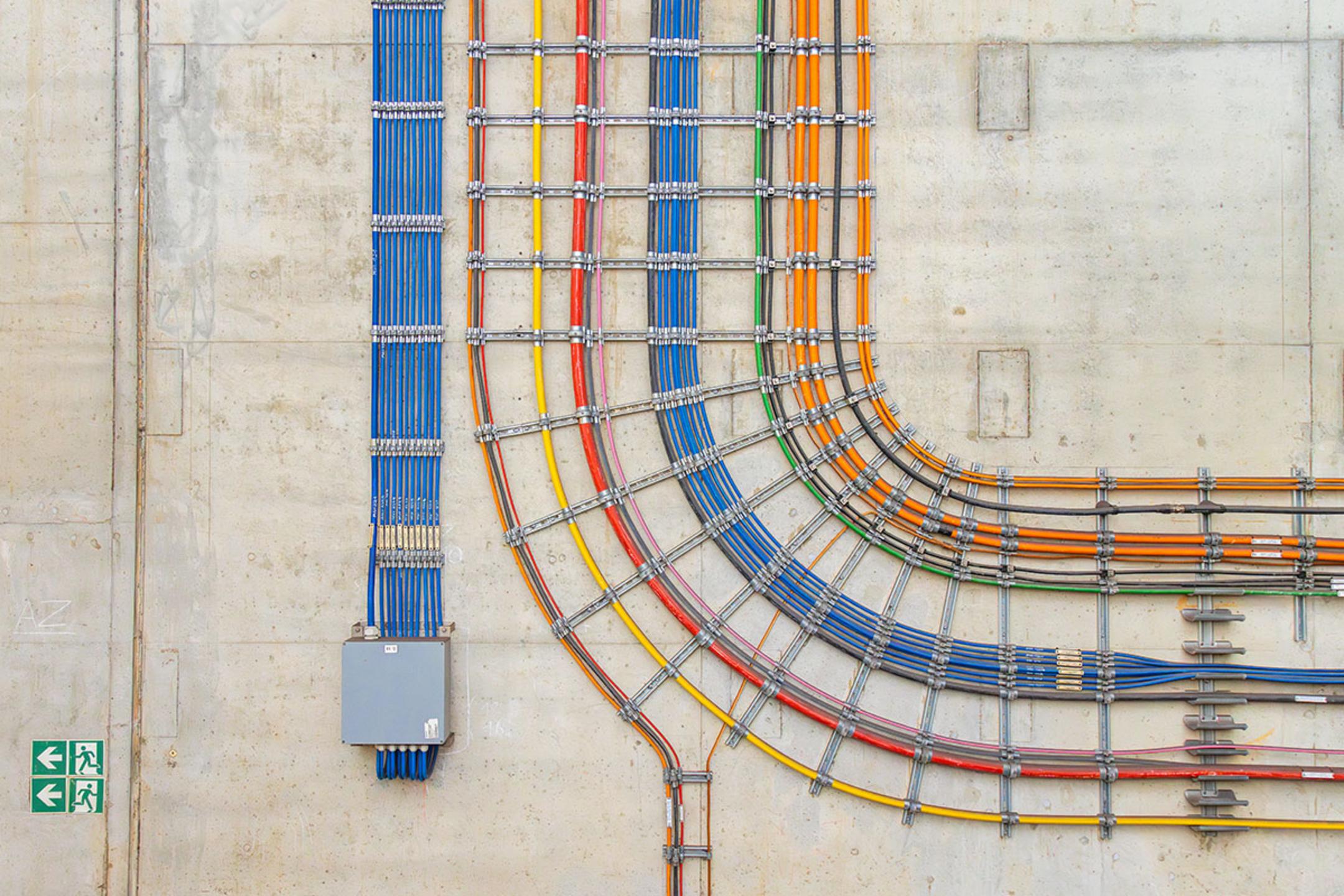 Farbcodierte Kabel in präziser Verlegung an einer Betonwand