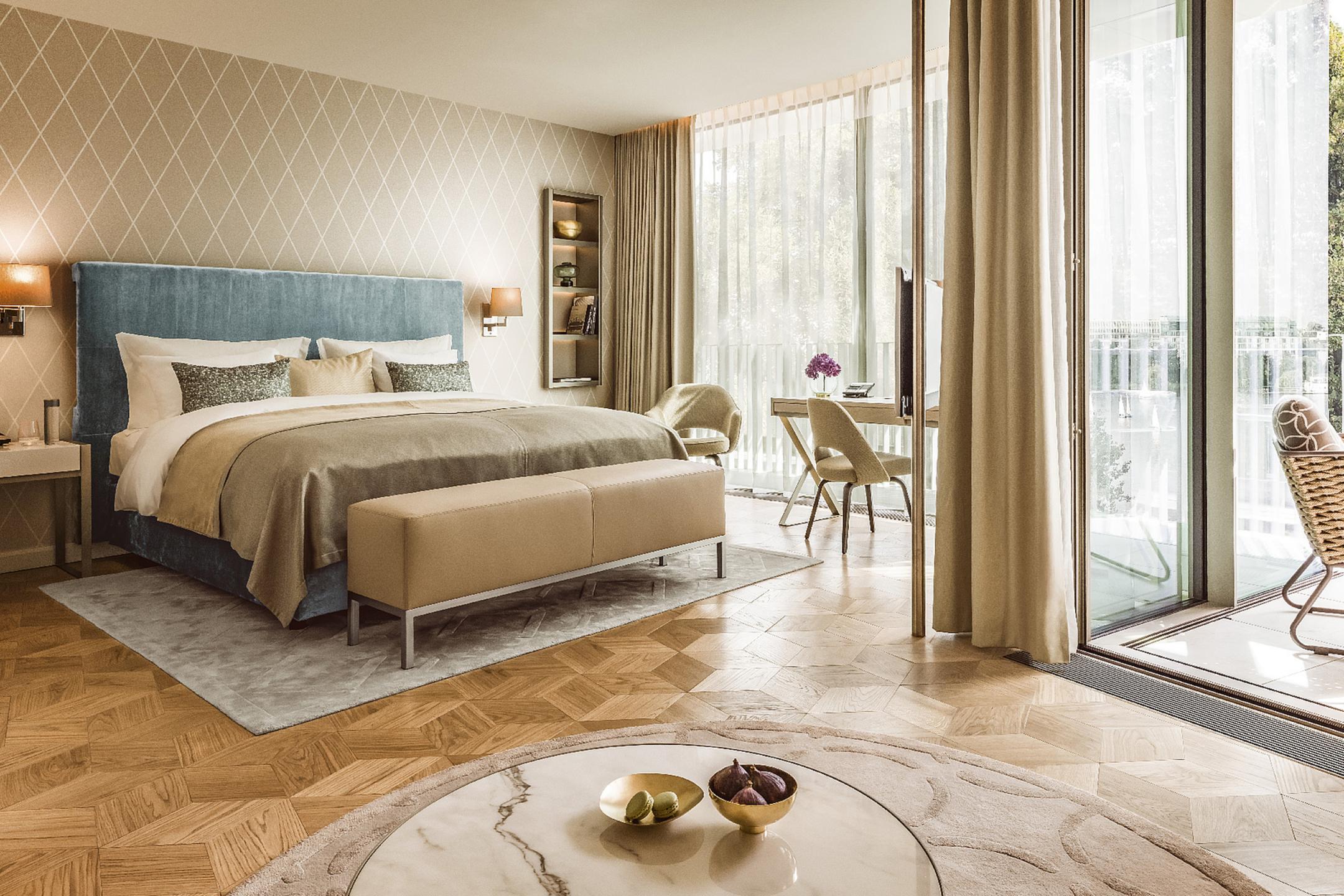 Elegantes Hotelzimmer mit großem Bett, modernem Design, Schreibtisch und bodentiefen Fenstern mit Balkon