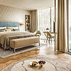 Elegantes Hotelzimmer mit großem Bett, modernem Design, Schreibtisch und bodentiefen Fenstern mit Balkon