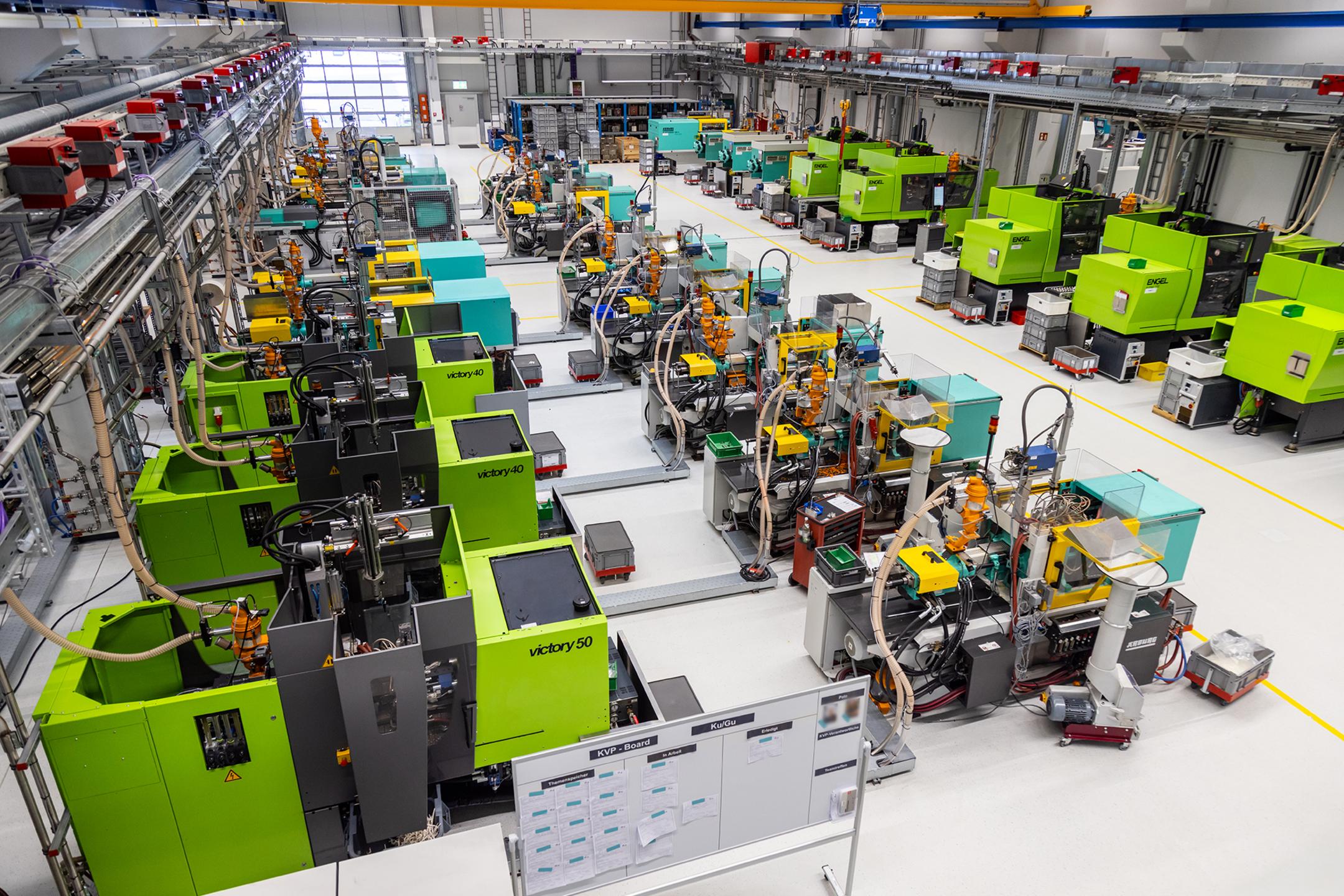 Totalansicht in moderne Produktionshalle mit mehreren Arbeitsplätzen und Maschinen.