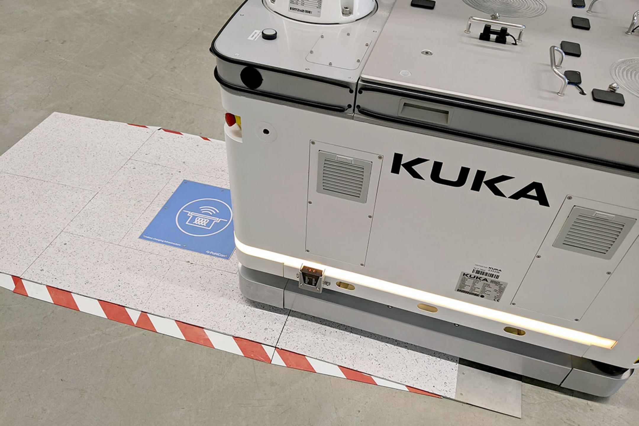 Automatisierter Transportroboter fährt über eine induktive blaue Ladeeinheit