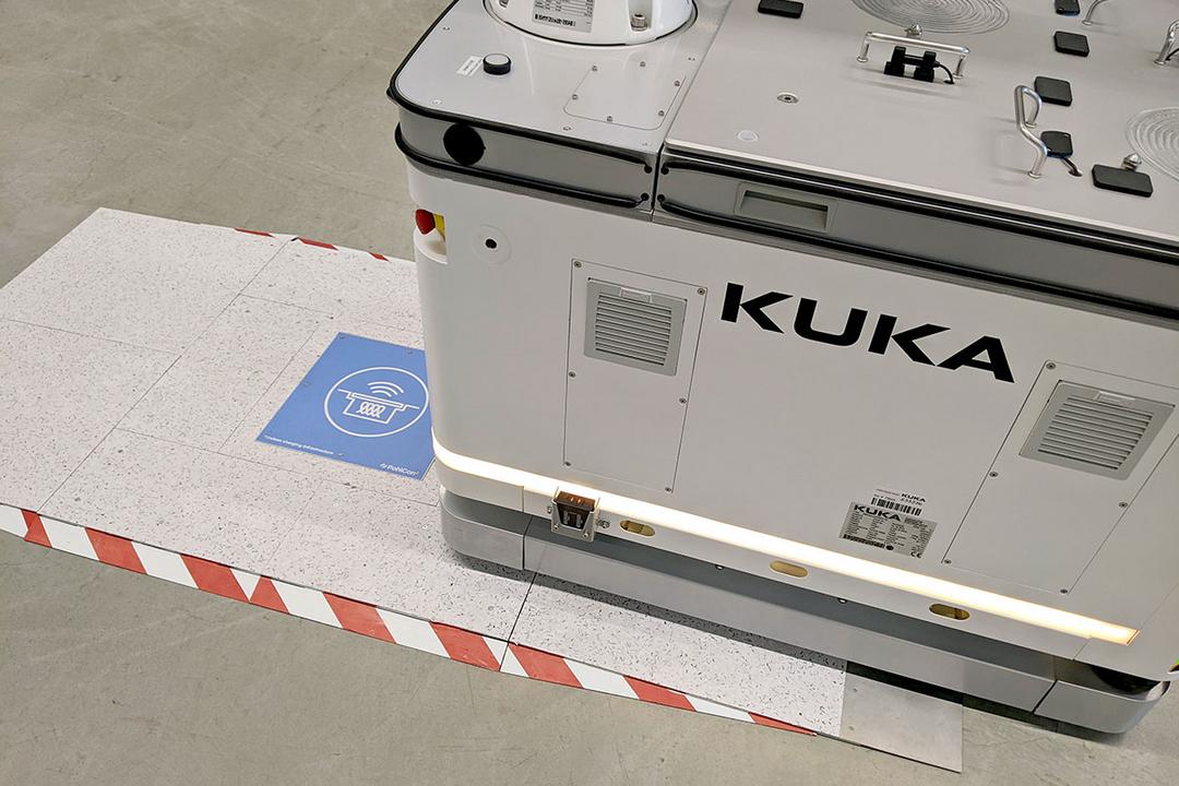 Automatisierter Transportroboter fährt über eine induktive blaue Ladeeinheit