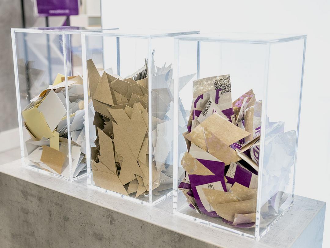 In 3 transparenten Kunststoffbehältern auf einer Betonfläche befindet sich das pappartige Schalrohr-Material.