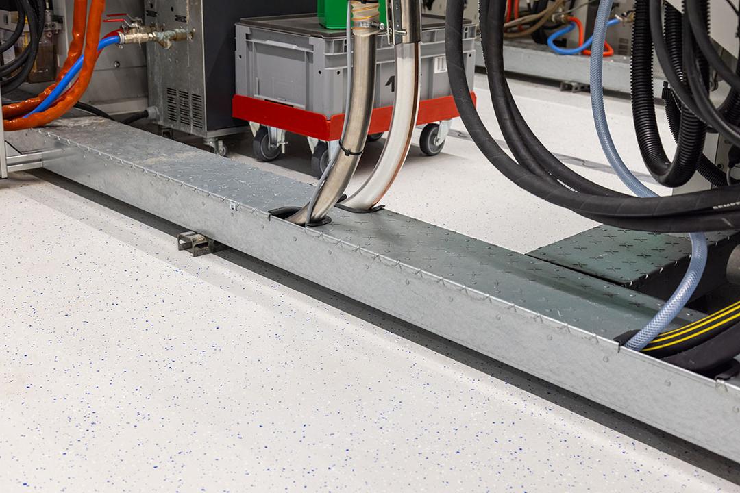 Bodenkanal aus Metall in Industrieumgebung mit herausgeführten Kabeln zur sicheren Leitungsführung am Maschinenplatz.