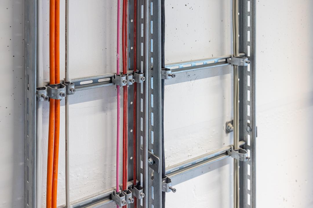 Detailansicht Kabelleiter, bestückt mit mehrfarbigen Kabel und befestigt mit Kabelschellen