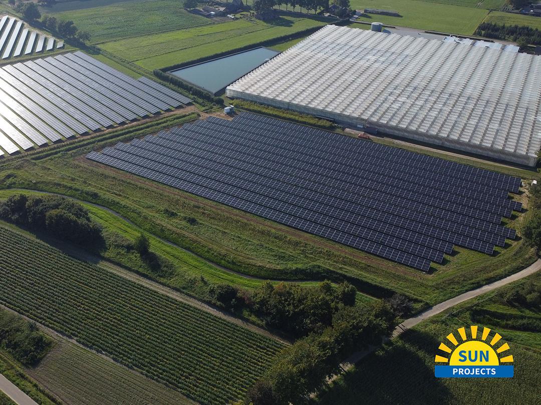 Luftaufnahme einer landwirtschaftlichen Fläche mit Solarpanelen und Gewächshäusern