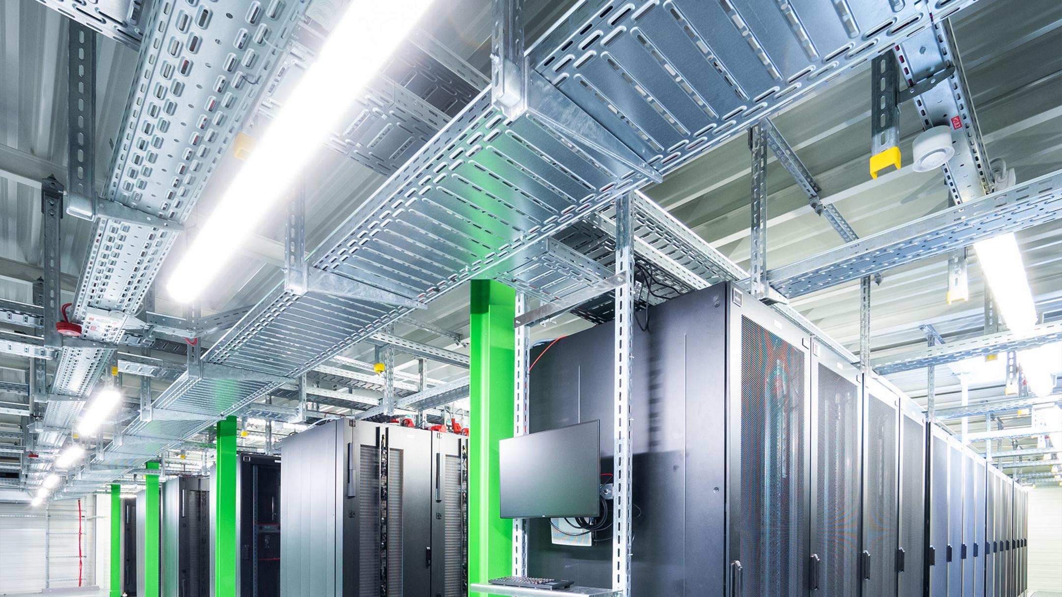 Rechenzentrum mit Serverracks, grünen Stützen und verzinkten Kabeltrassen zur strukturierten Kabelführung unter der Decke.