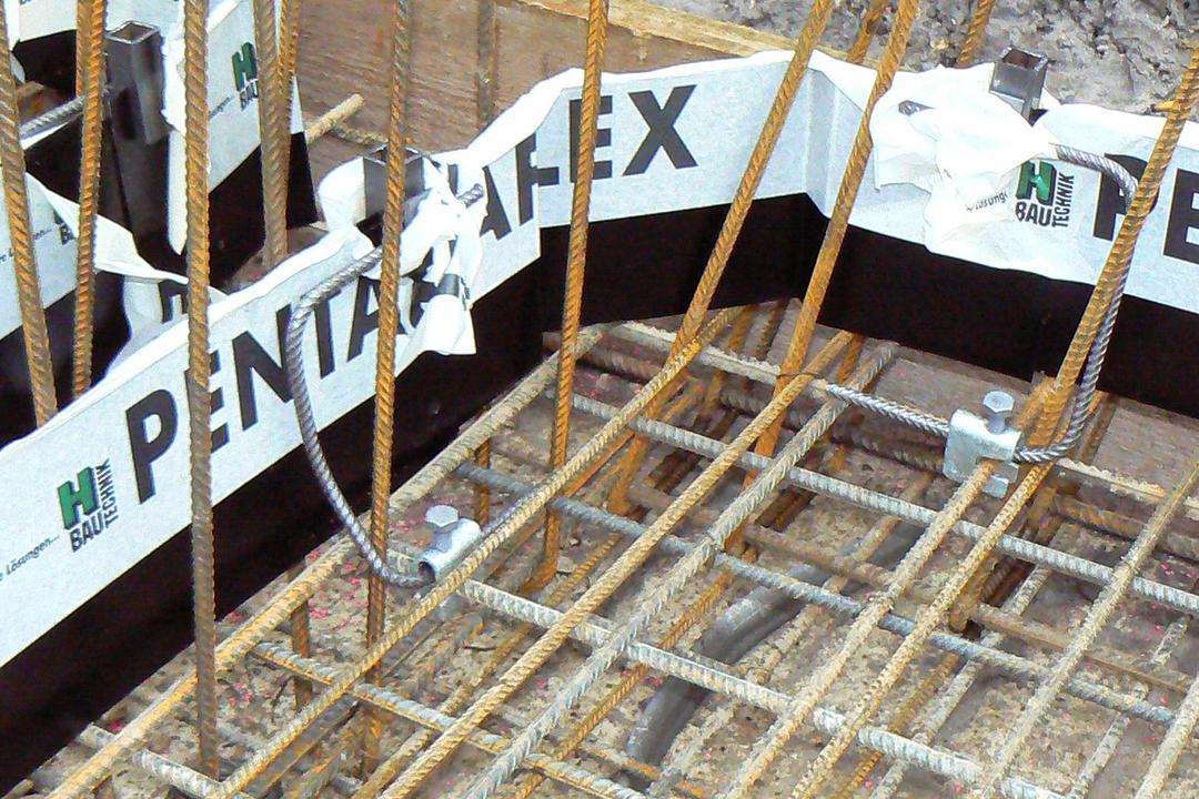 Bewehrung aus Stahlstäben auf Baustelle mit Schalung und Abdichtungsband „Pentaflex“.