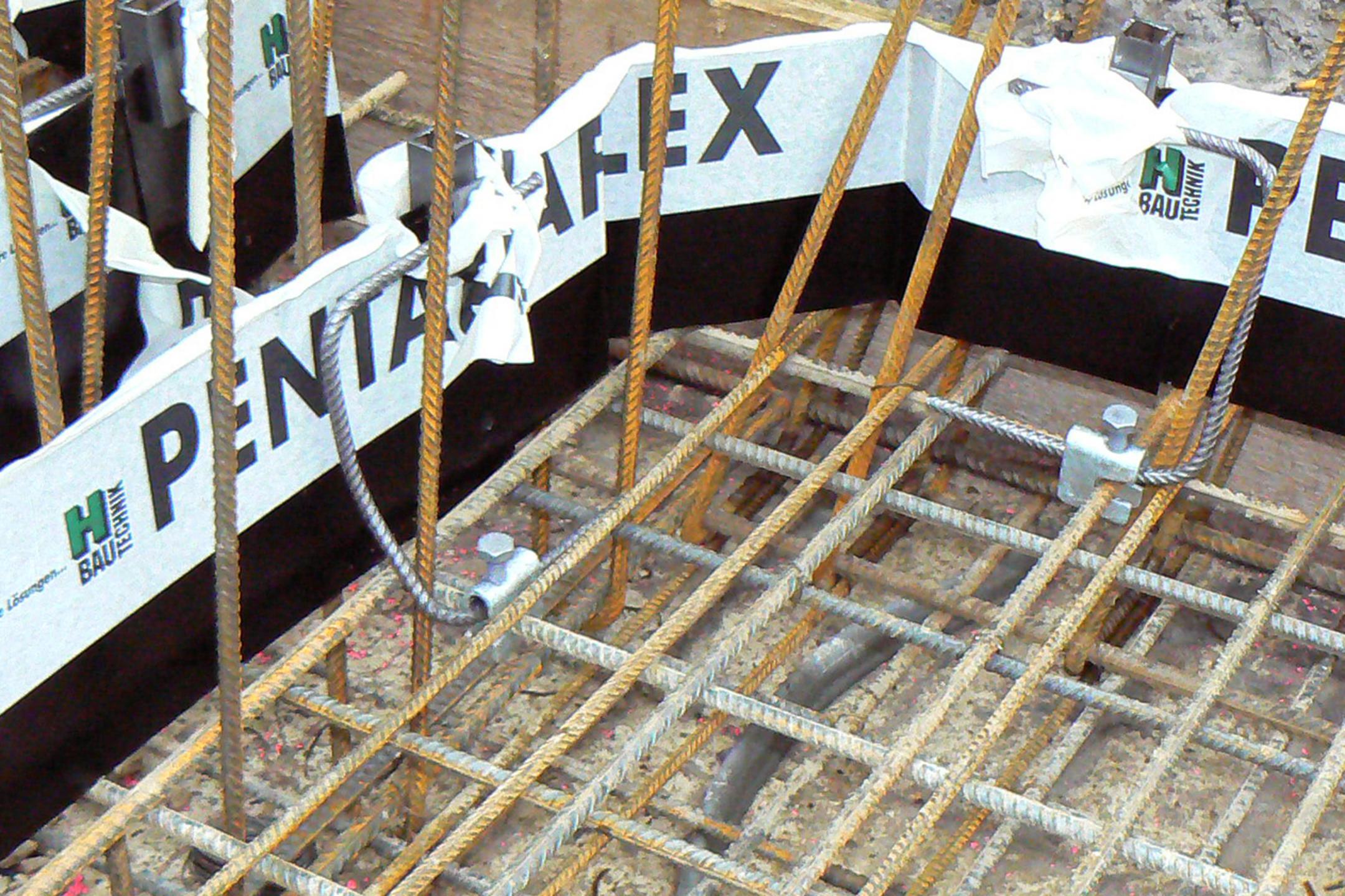 Bewehrung aus Stahlstäben auf Baustelle mit Schalung und Abdichtungsband „Pentaflex“.