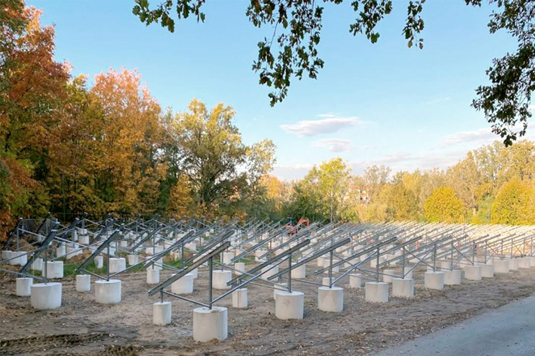 Montierte Stahlunterkonstruktion für Solarthermieanlage auf zylindrischen Betonfundamenten in einem offenen Gelände mit herbstlicher Vegetation