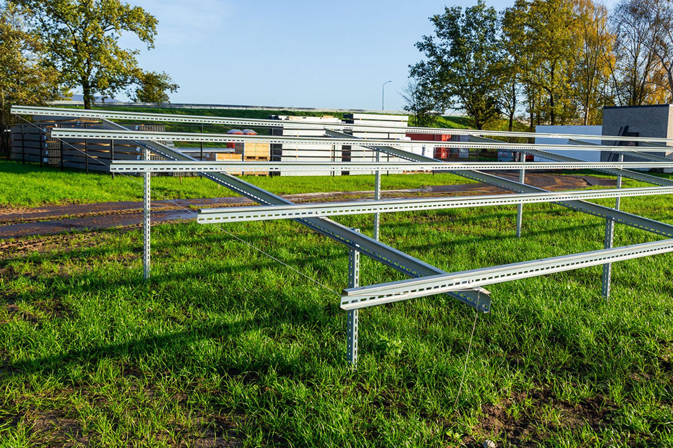 Ein Gerüst aus Stützen im Boden und Quer- und Längsträgern auf einer grünen Wieso