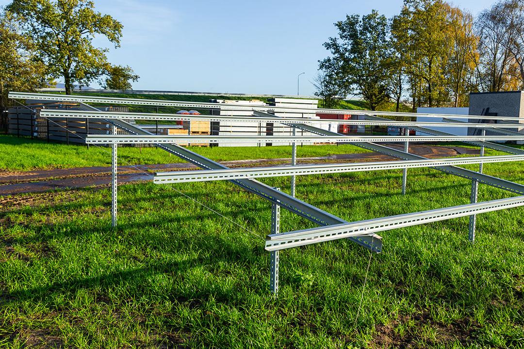 Ein Gerüst aus Stützen im Boden und Quer- und Längsträgern auf einer grünen Wieso