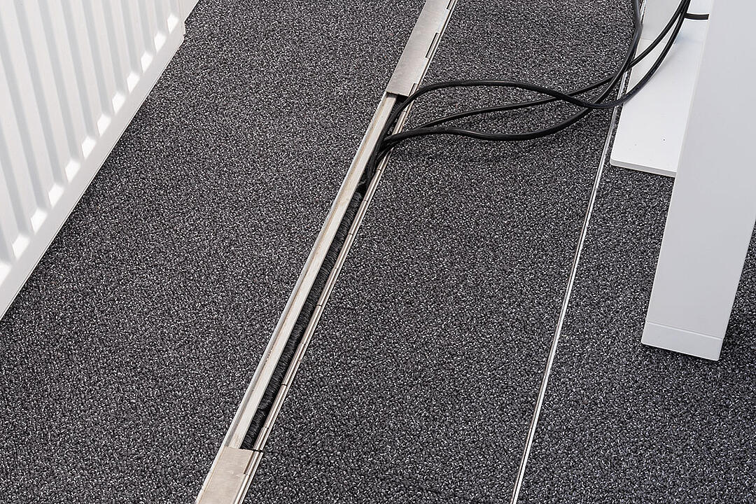 Das in den Boden eingelassene Kanalsystem für Kabel, geschlossen, in einem Büro.