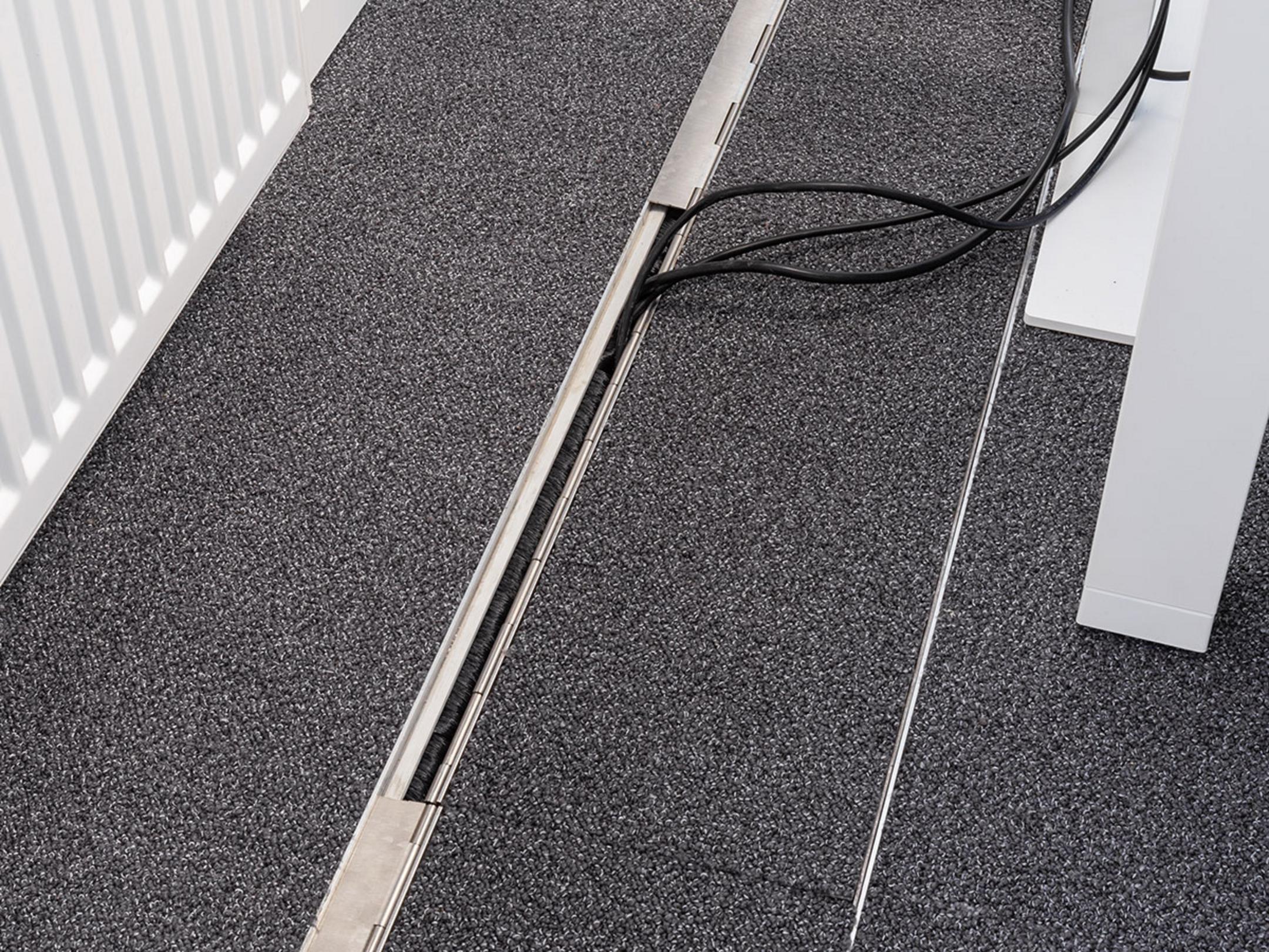 Das in den Boden eingelassene Kanalsystem für Kabel, geschlossen, in einem Büro.